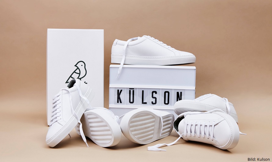 weiße Sneaker liegen auf dem Boden, dahinter steht ein Schild mit der Aufschrift Kulson